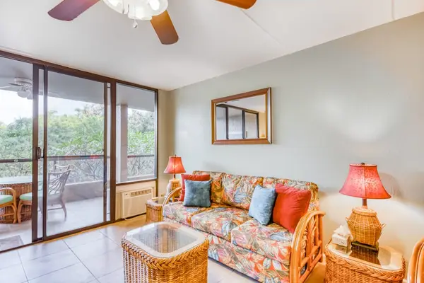 Detailed living room view featuring a comfortable sofa, warm accent lamps, wicker coffee table, and massive sliding glass doors to the balcony! 🛋️🌅✨
