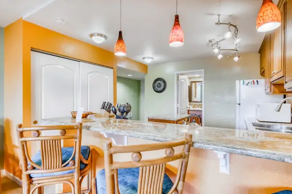 Spacious kitchen breakfast bar island featuring wooden barstools with blue cushions, pendant light fixtures, and a clean culinary workspace! 🍽️