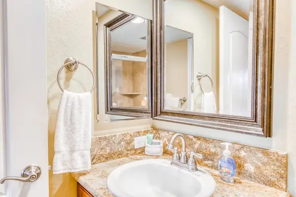 Functional bathroom vanity featuring a stone countertop, undermount oval sink, wood-framed mirrors, and a convenient hand towel station! 🚰📐