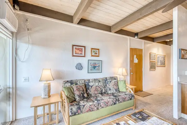 Spacious living room layout featuring a patterned couch, wood accents, warm lamp lighting, and gorgeous high vaulted ceiling beams extending through the home! 🛋️🪵✨🌴😎
