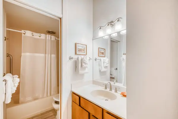 Detailed bathroom setup featuring a spacious vanity counter, large mirror, bright overhead lighting, and a full bathtub shower station! 🚿🧼✨🌴