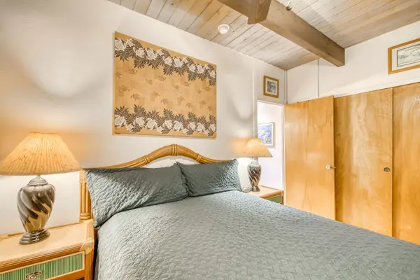 Detailed bedroom scene featuring a comfortable bed, warm lamp lighting, decorative wall tapestry, and ample wooden closet storage space! 🛏️🚪✨🌴