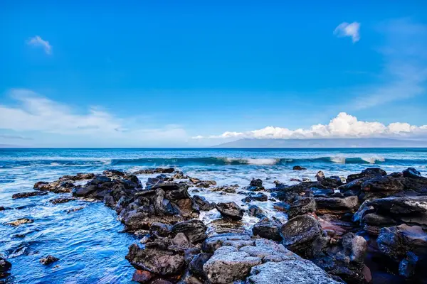 Serene Rocky Coastline Beneath Blue Island Skies