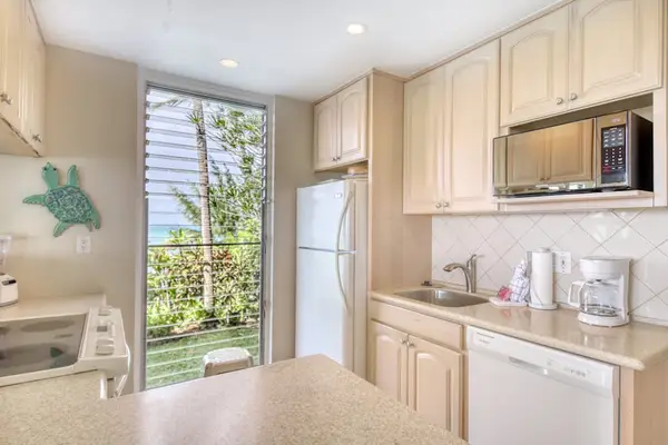 Bright kitchen offers practical counters, appliances, and garden views nearby