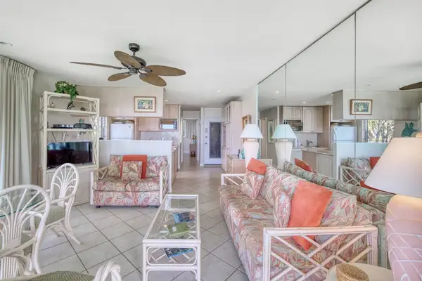 Sunlit living area presents relaxed seating, curtains, and garden views