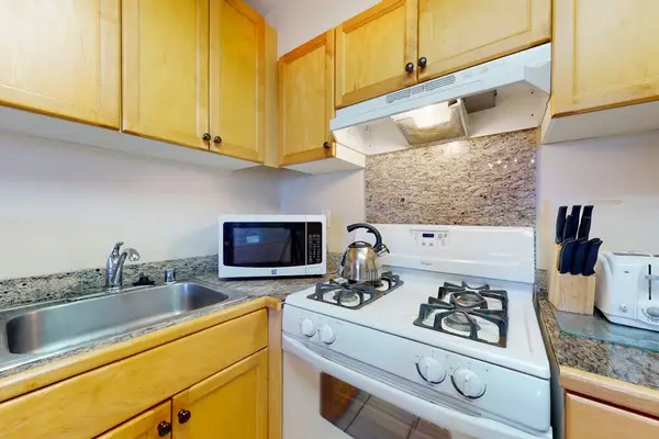 Kitchen Corner Featuring Gas Range, Microwave & Granite Countertops