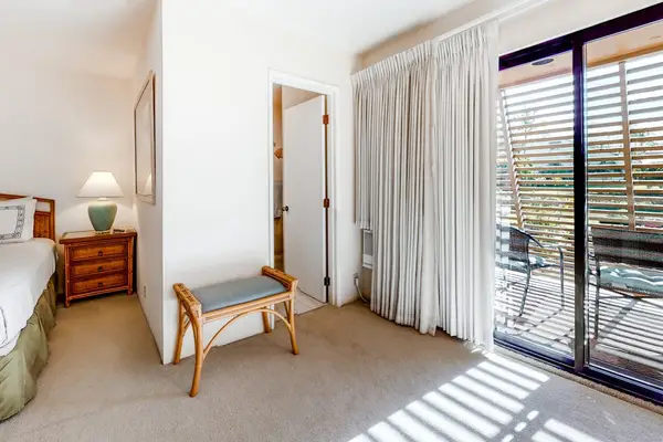 This bedroom offers comfortable furnishings abundant sunlight and balcony access