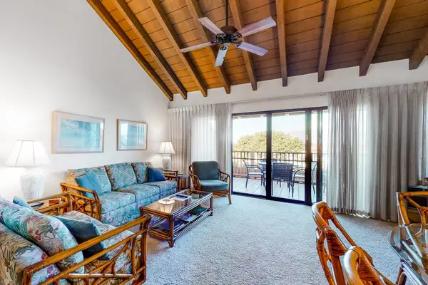 Island-inspired living room features wood ceiling sofa and balcony doors