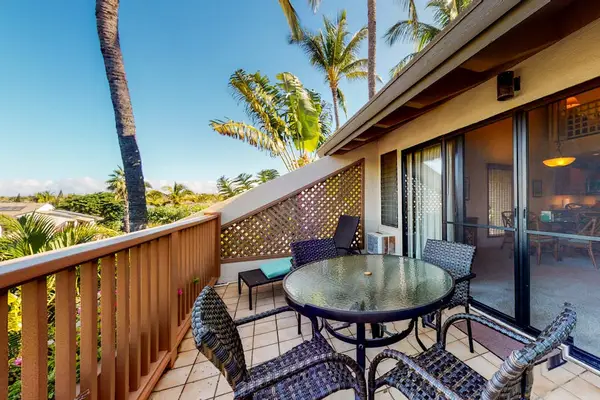 Balcony dining set overlooks palm trees and Maui resort landscaping