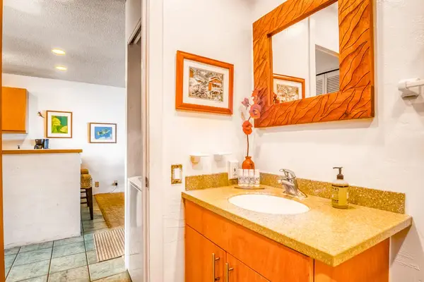 Bright bathroom vanity featuring a single sink, large mirror, and convenient cabinet storage