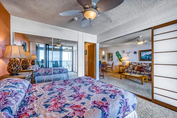 Comfortable bedroom setup featuring a cozy bed, ceiling fan, and full-length mirrored closets
