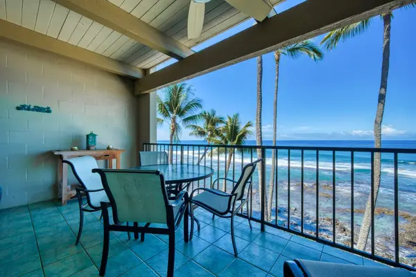 Outdoor balcony dining table setup with beautiful ocean and palm tree views at twilight