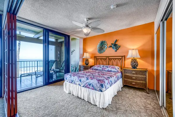 Bright bedroom featuring a comfortable bed, accent wall, and sliding doors to a private balcony!
