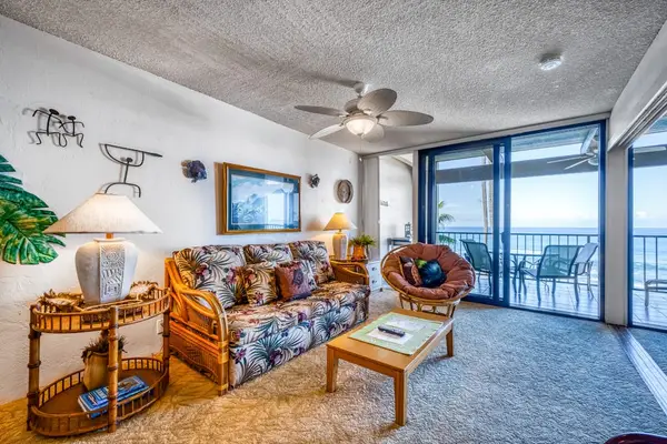 Inviting living room featuring comfortable seating, a ceiling fan, and sliding doors to an ocean-view balcony