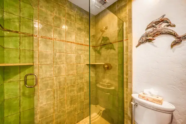 Tiled walk-in glass shower stall featuring built-in corner shelves and modern finishes