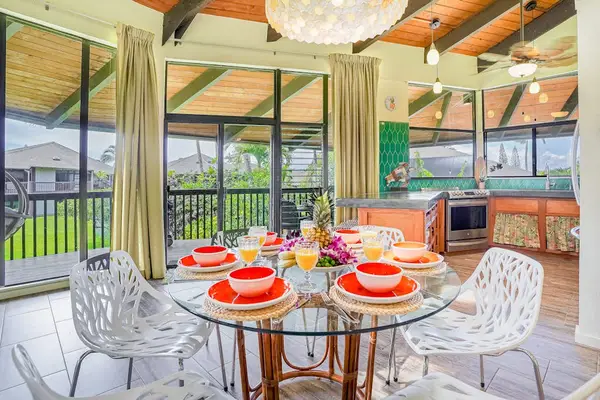Elegant dining area with vaulted wood ceilings and tropical touches, opening to a screened lanai