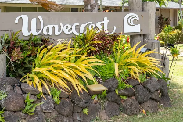 Wavecrest sign stands among tropical plants and volcanic stone landscaping