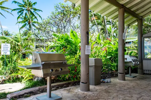 Covered BBQ area features grill counter and tropical garden surroundings
