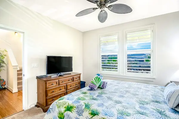 Guest bedroom with king bed, ceiling fan and a flat screen tv.