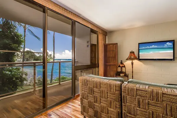 Lovely living room with a flat screen tv and light coming in from the lanai and views of the Pacific Ocean.
