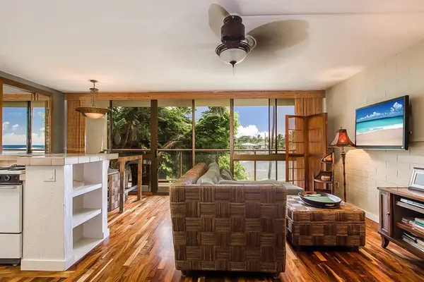 Lovely living room with a flat screen tv and light coming in from the lanai and views of the Pacific Ocean.