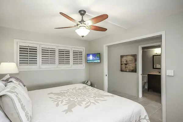 Master bathroom with king bed, flat screen tv and a ceiling fan.