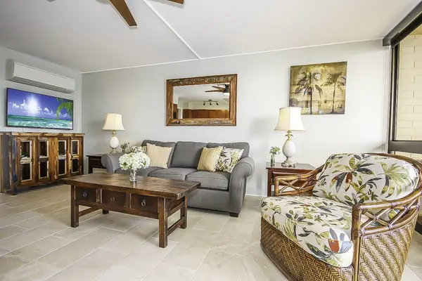 Lovely open air living room with comfortable furniture and natural light streaming in from glass doors leading to the lanai.