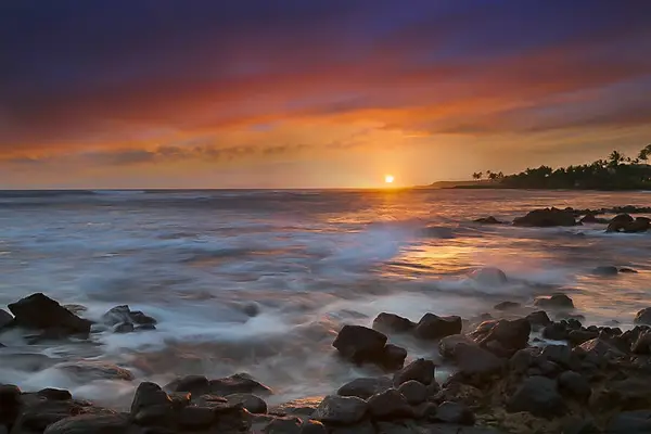 Watch breathtaking pink, orange, and purple sunsets as the Pacific Ocean waves crash against the rocky shoreline, creating an unforgettable island backdrop.