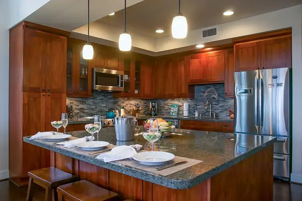 High-end and high-style, the open kitchen boasts handsome cherry cabinets, granite counters, stainless appliances, and a large island with seating for three.