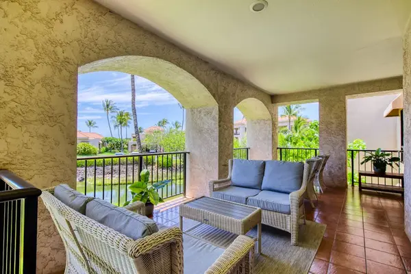 Covered balcony overlooks tropical greenery with comfortable outdoor seating