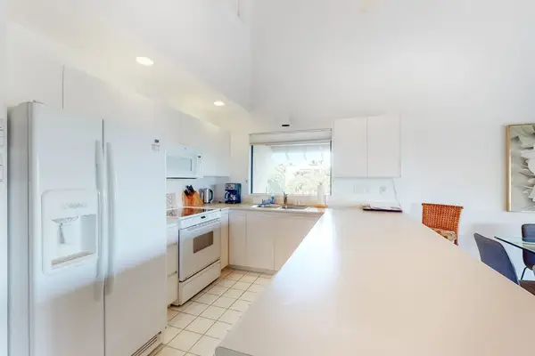 Bright kitchen offers generous counters, white cabinetry, and island seating