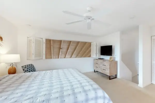 Showcases king bed, television, and sloped wood ceiling