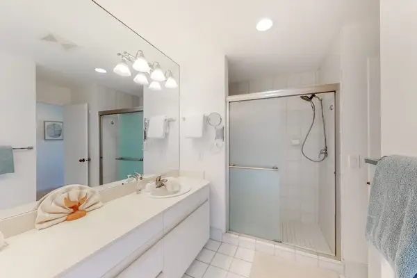 Full bathroom features glass shower, vanity, and bright mirror lighting