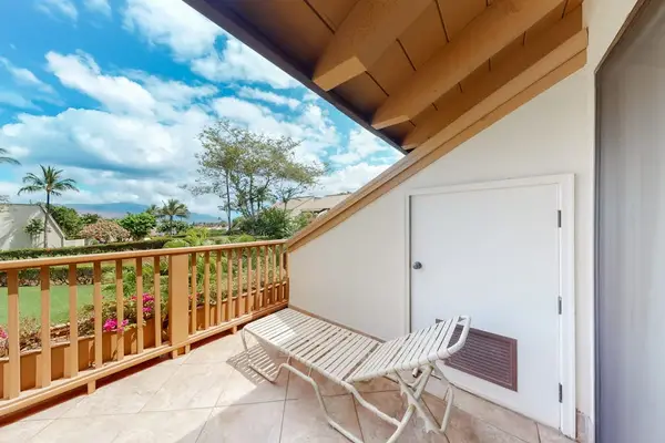 Balcony lounge chair overlooks tropical gardens beneath a covered roofline