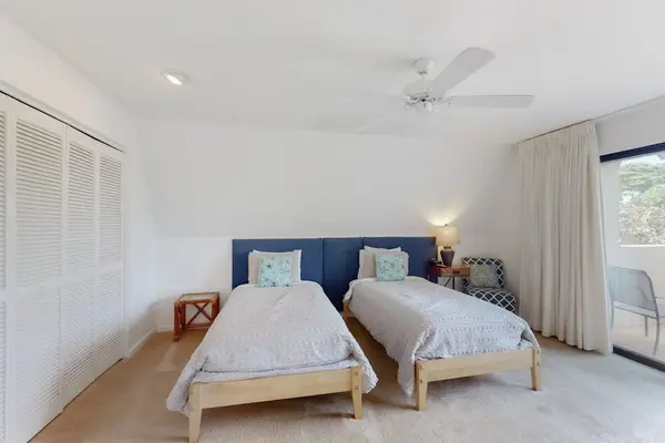 This bedroom features twin beds, ceiling fan, and bright windows