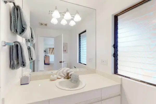Full bathroom vanity includes dual sinks, mirror, and natural light