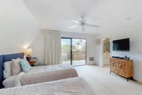 Opens onto balcony with television, dresser, and fan