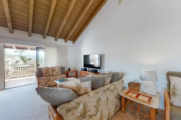 Comfortable living room seating faces television beneath vaulted wood ceiling