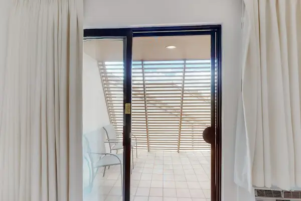 Sliding doors open toward balcony seating and peaceful tropical surroundings