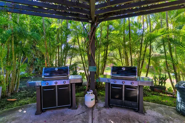 Outdoor BBQ station features twin grills beneath lush garden greenery