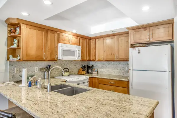 Kitchen island offers generous workspace beside stools and bright cabinetry