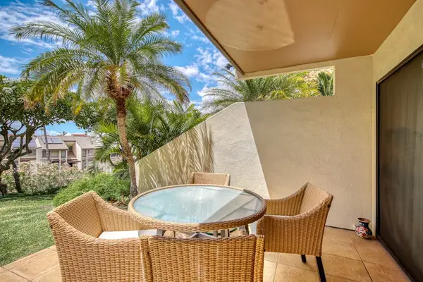 Patio dining set overlooks palms and colorful tropical resort gardens