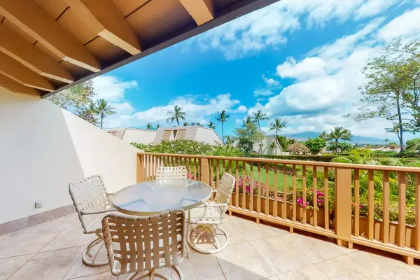 Balcony dining area overlooks palms, gardens, and distant island views