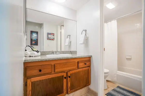 Bathroom vanity with ample counter space, large mirror, and warm wooden cabinetry