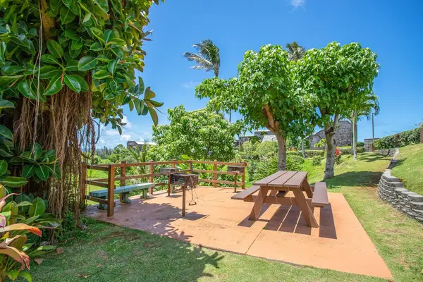 Community outdoor grilling area with picnic tables set amidst tropical landscaping