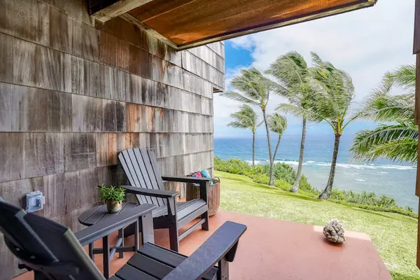Covered oceanfront lanai with outdoor seating overlooking tropical palms and coastal waters