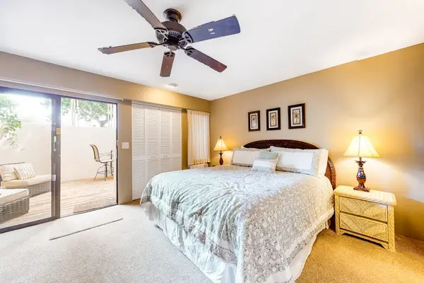 Bedroom features restful bedding and convenient tropical garden views