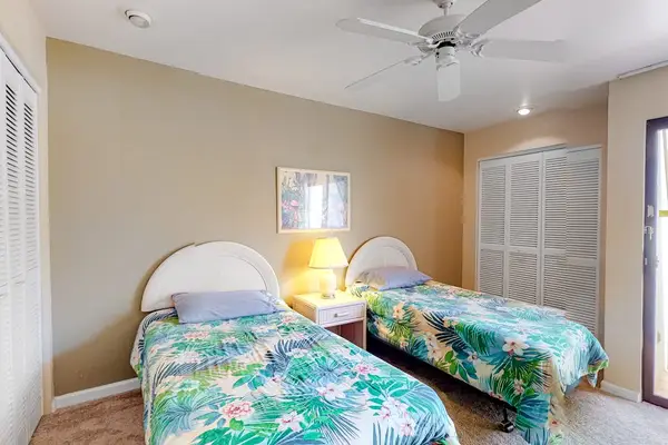 This bedroom features twin beds ceiling fan and natural light