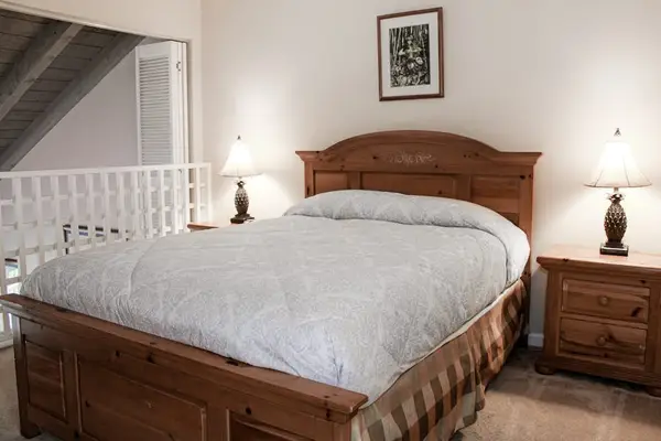Bedroom features comfortable bed nightstands ceiling fan and artwork