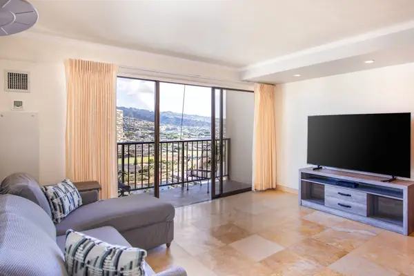 Bright open-concept living room with a private balcony, Smart TV, and panoramic city and mountain views.